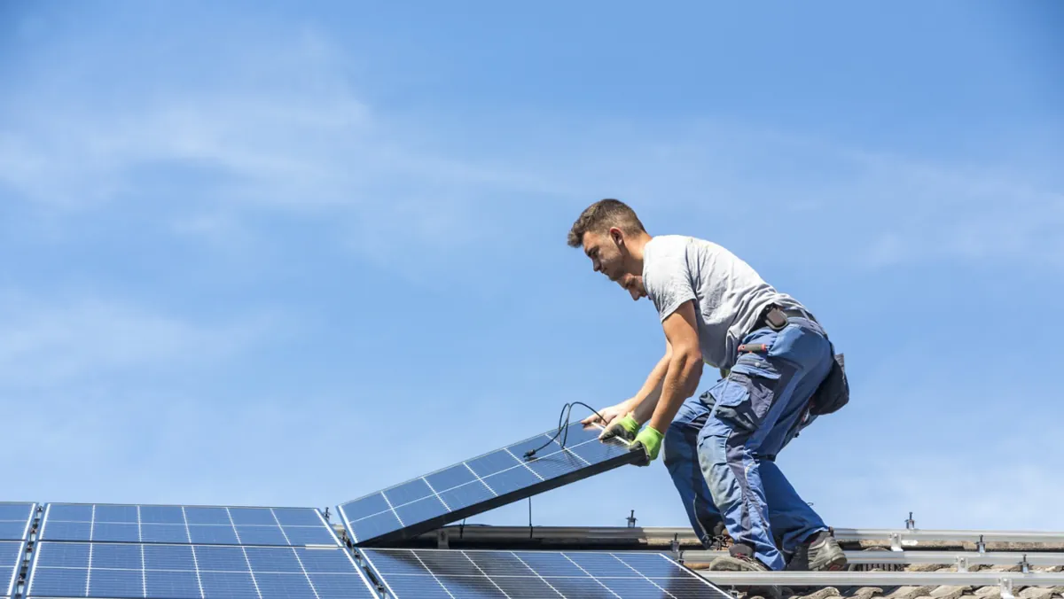 A man is installing solar panels on a roof.