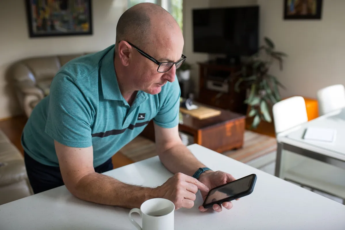 Solar panel monitoring app open on a phone at a kitchen table